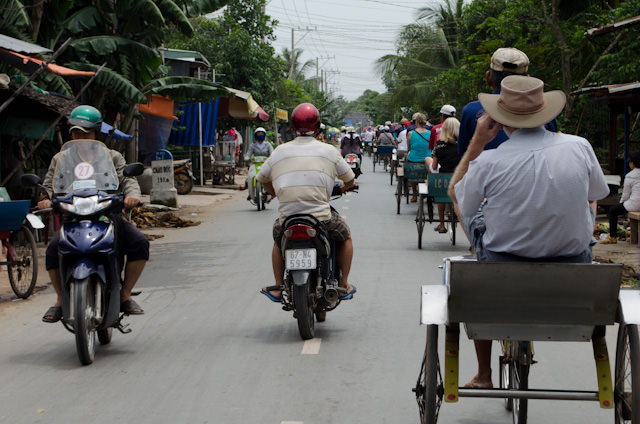 A procession of rickshaws make their way through the streets of Tan Chau, Vietnam. Photo © 2013 Aaron Saunders