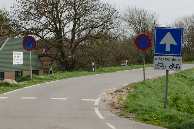 What do these signs mean on this road in Hoorn, Netherlands? From left to right: No Stopping (both signs); proceed in this direction; bicycles share the road with motorbikes. Photo © 2014 Aaron Saunders